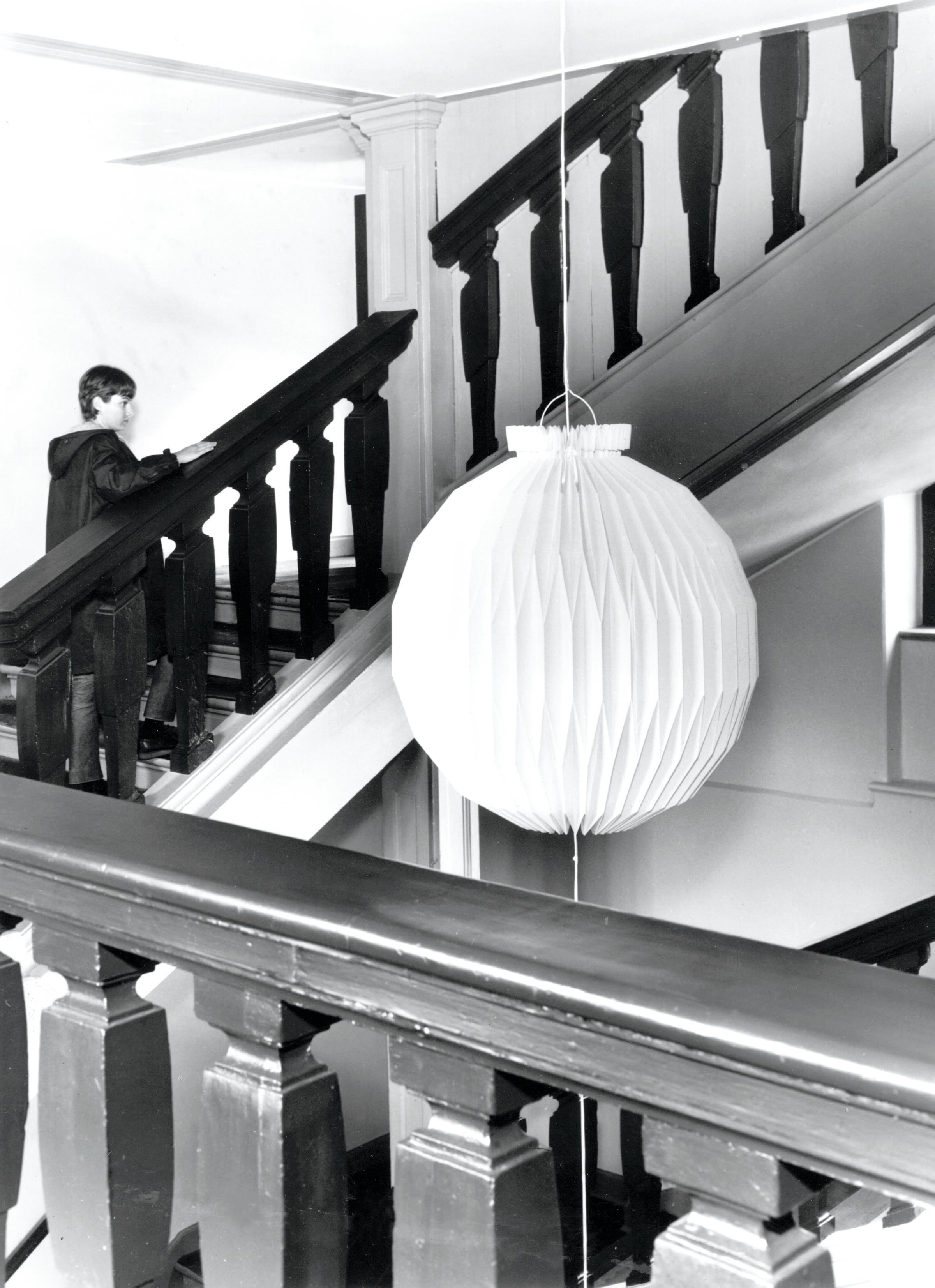 Sort/hvid billede af trappe opgangen på kunstakademiet i København med en kæmpe 107 pendel hængende ned fra loftet